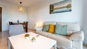 Una sala de estar con un sofá, una mesa de comedor y un cuadro en la pared.