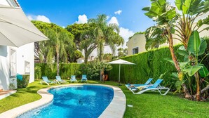 A swimming pool with blue water, surrounded by a well-maintained lawn and various plants. - Villa Moongate - Three Bedroom Villa, Sleeps 6 (Calahonda)