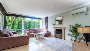 A spacious living room with a large window, a fireplace, and a modern sofa set. - Villa Moongate - Three Bedroom Villa, Sleeps 6 (Calahonda)
