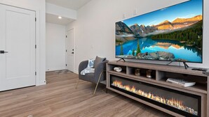 Una sala de estar moderna con un televisor de pantalla plana grande, una chimenea y una zona de estar acogedora.
