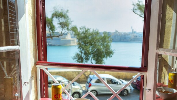 Una ventana con vistas a un cuerpo de agua y coches estacionados.