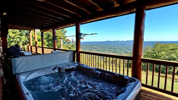Un jacuzzi en una terraza de madera con vistas a montañas.