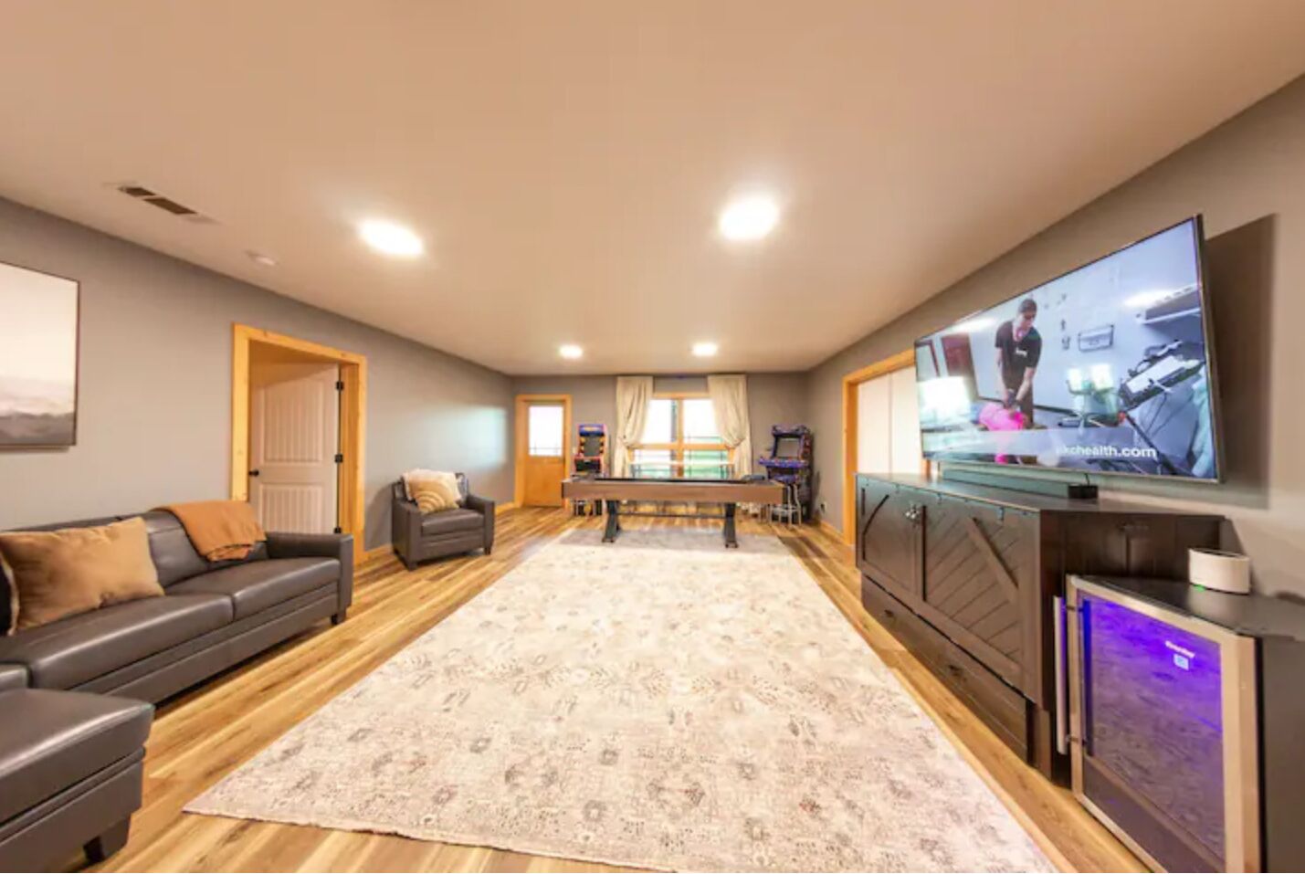 A spacious living room with a pool table, a sofa, a television, and a gaming console.