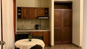A compact kitchen with wooden cabinets, a dining table with a white tablecloth, and a built-in oven. - Luna de Plata (Quetzaltenango)