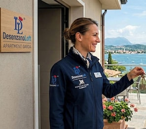 A person standing at a hotel entrance with a sign reading 'Desenzano Loft APARTMENT GARDEN'. - Desenzanoloft Oasis  (Desenzano del Garda)
