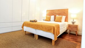 Ein modernes Schlafzimmer mit einem großen Bett, einem Holz-Kopfteil, zwei Nachttischen mit Lampen und einem großen Kleiderschrank.