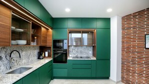 Eine moderne Küche mit grünen Schränken, einer Granit Arbeitsplatte, einem eingebauten Ofen und einer Wand mit Backsteinausbau.
