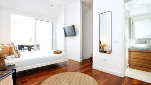 A modern bedroom with a bed, bedside table, and a mounted TV. - GREEN FARO : MODERN DUPLEX WITH A BLISS TERRACE (Faro)