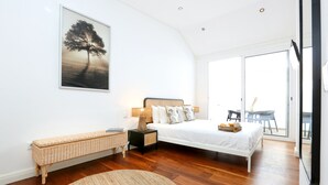 A bedroom with a bed, bedside tables, a bench, and a large window. - GREEN FARO : MODERN DUPLEX WITH A BLISS TERRACE (Faro)