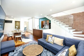 Een moderne woonkamer met een bank, salontafel en een eethoek met stoelen en een tafel.