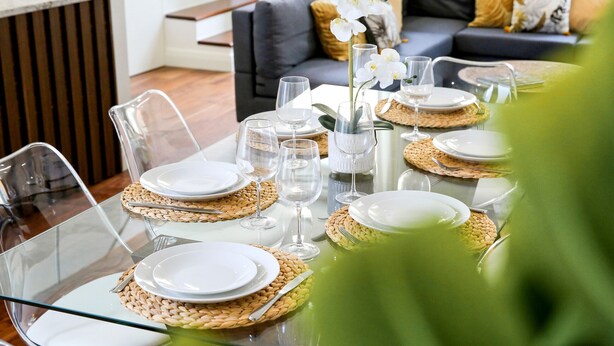 Una mesa de comedor dispuesta con platos, vasos y un florero.