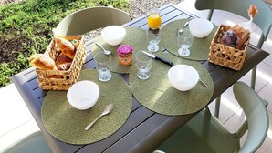 An outdoor dining area with a table set for two, featuring green placemats, white plates, and a basket of bread. - Rêves de mer en Tout Compris (Linguizzetta)