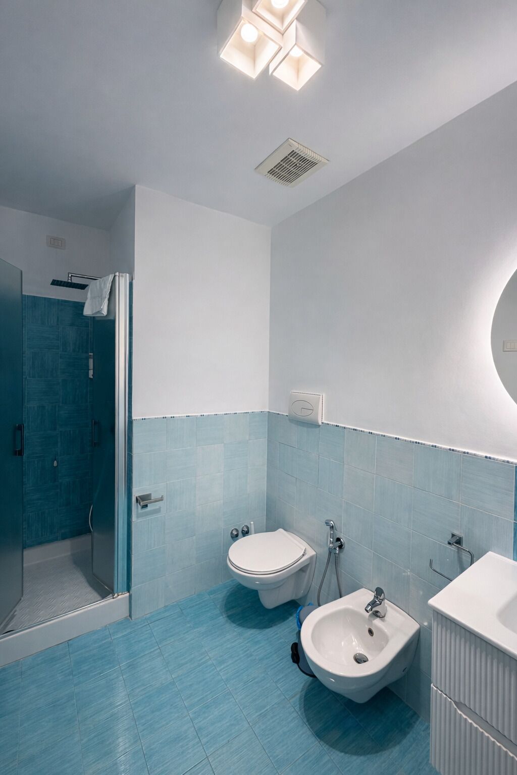 A modern bathroom with a shower, toilet, bidet, and sink.