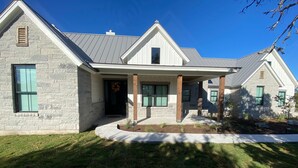 A modern two-story house with a stone facade, a covered porch, and a well-maintained lawn.