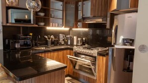 A modern kitchen with wooden cabinets, a black countertop, stainless steel appliances, and a built-in oven.