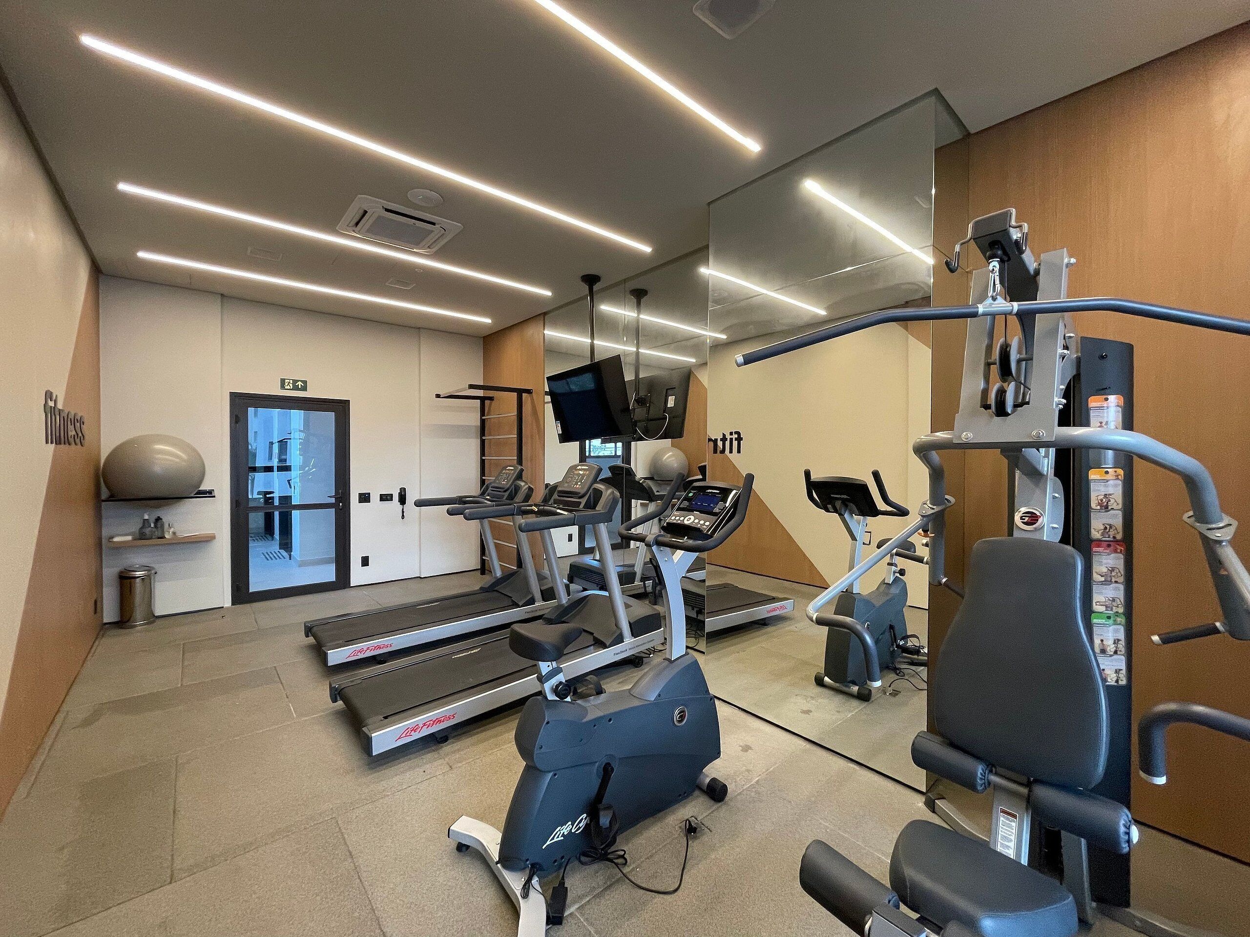 Un gimnasio moderno con cintas de correr, elípticas y máquinas de pesas.
