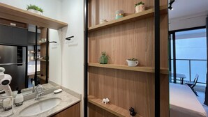 Une salle de bain moderne avec un grand miroir, un lavabo et des étagères en bois ornées d’objets décoratifs.