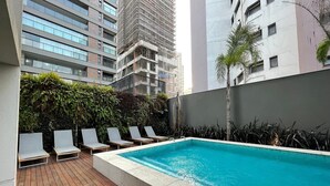 Un espace piscine aménagé sur le toit, avec des chaises longues et une terrasse en bois.