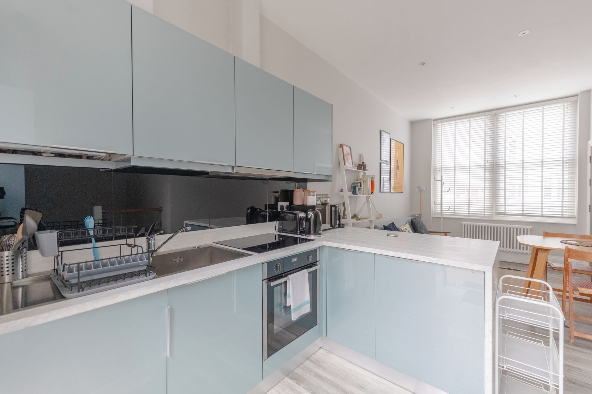 A modern kitchen with light blue cabinets, a central island, and a dining area with a table and chairs.