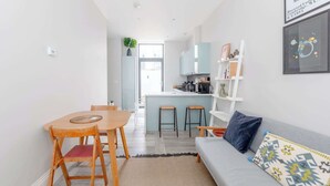 A modern apartment with a dining area, kitchen, and living room. - Chic 1BD Flat with Patio, 2 Mins from Barons Court (London)