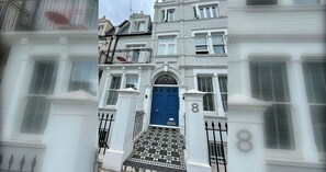 Um edifício tradicional com porta azul, paredes brancas e o número 8 na fachada.