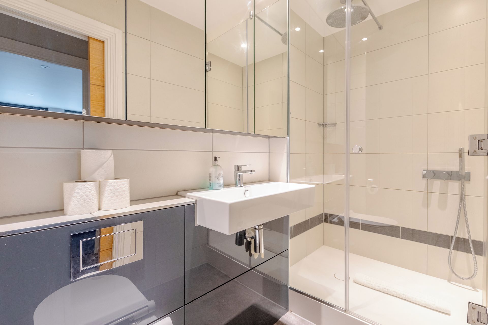 A modern bathroom with a glass shower enclosure, a white sink, and a toilet.