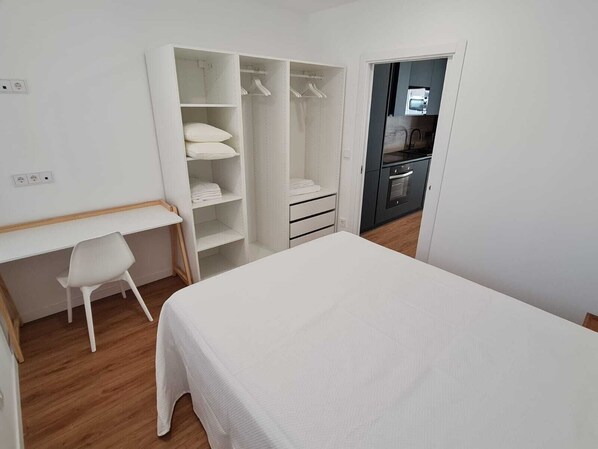 A bedroom with a bed, a desk, a chair, a wardrobe, and a kitchenette. - BR Silgar Suites (Sanxenxo)