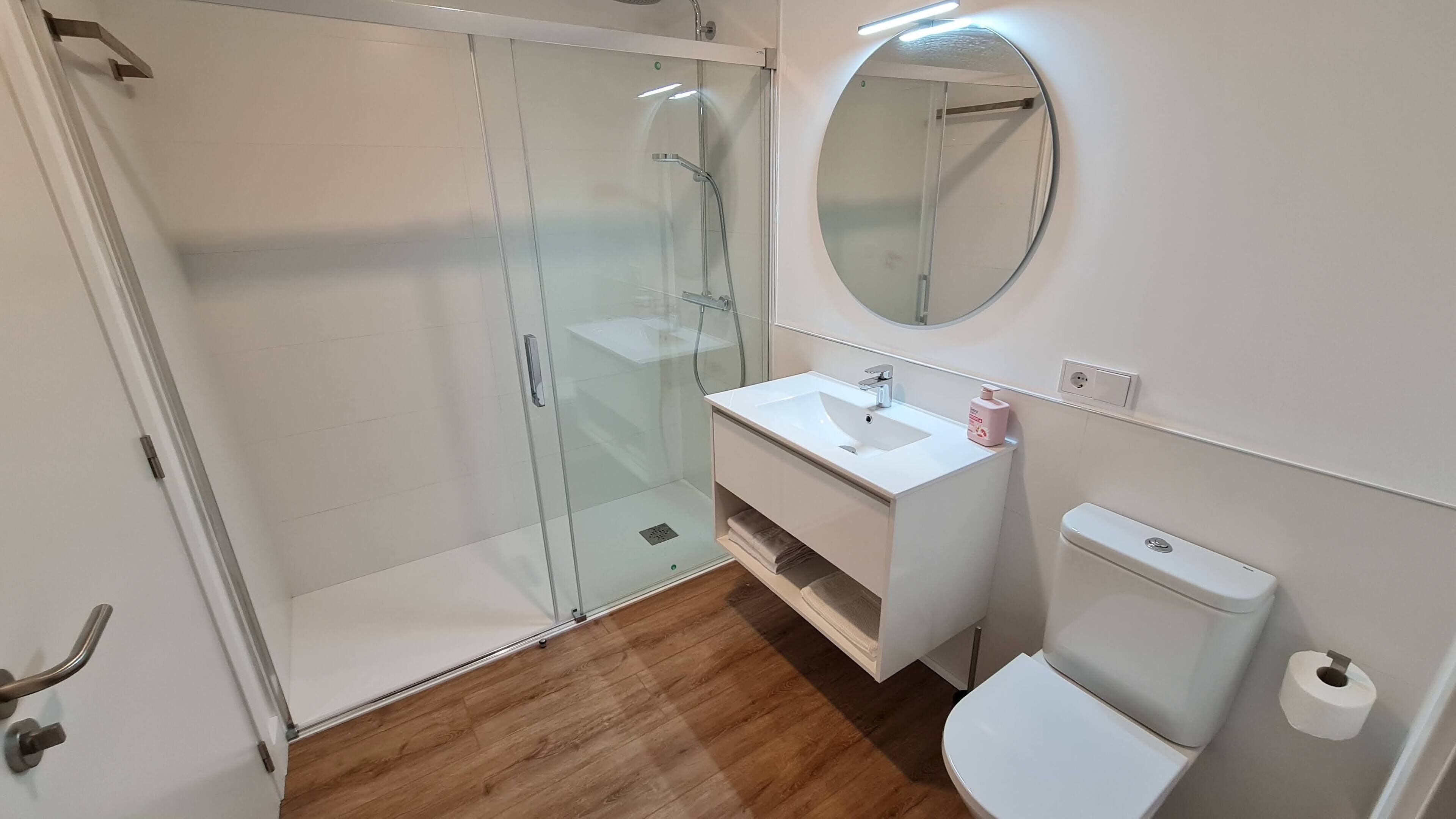 Un bagno moderno con cabina doccia in vetro, un lavandino bianco e un water.