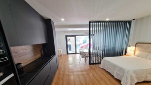 Une chambre d’hôtel moderne équipée d’une kitchenette, d’un lit, d ’un coin repas et offrant une vue sur l’extérieur.