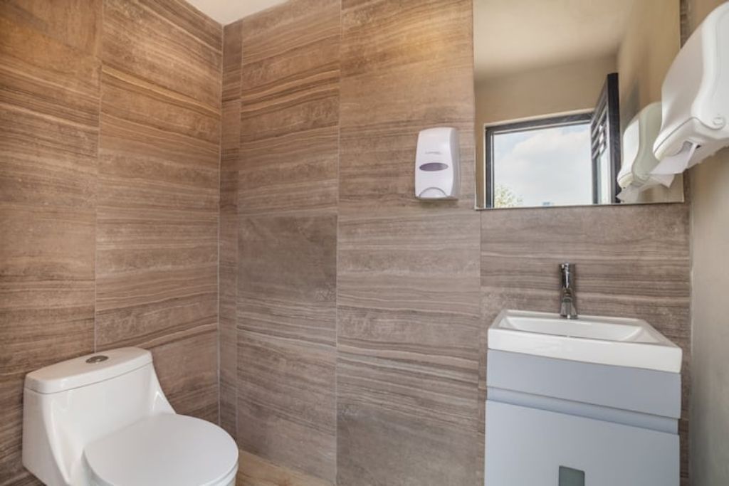 Ein modernes Badezimmer mit Toilette, Waschbecken und Handtrockner.