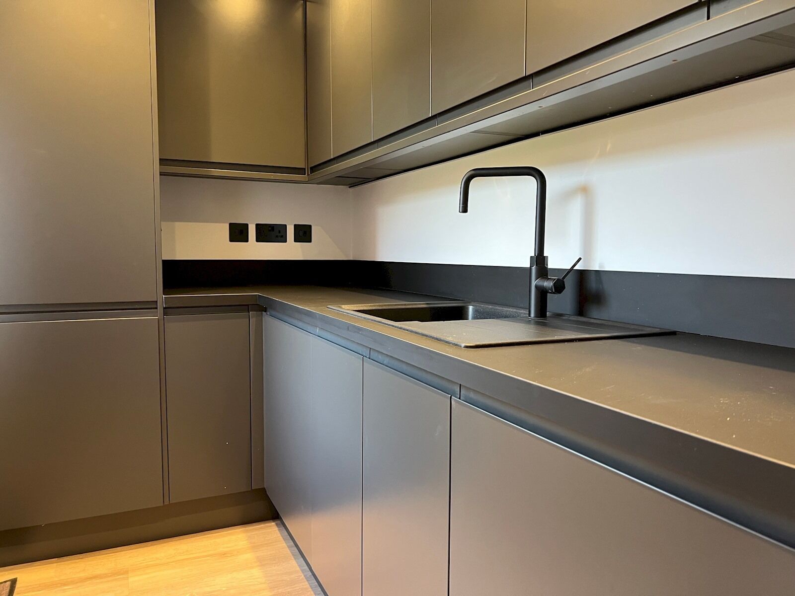 A modern kitchen with stainless steel cabinets, a black faucet, and a countertop.