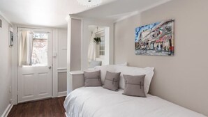 A bedroom with a white bed, a door, a window, and a painting on the wall. - Pet-Friendly 1855 Garden Retreat • Savannah (Savannah)
