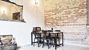 A room with a brick wall, a wooden table with chairs, a vintage radio, and a small bear figurine. - Casa particular vintage (Rome)