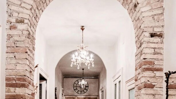 A hallway with brick walls, wooden flooring, and a chandelier. - Casa particular vintage (Rome)
