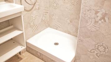 A bathroom with a shower area, a sink, and a toilet.