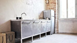A kitchen with a stainless steel countertop, a refrigerator, and a window with a view of the outside. - Casa particular vintage (Rome)
