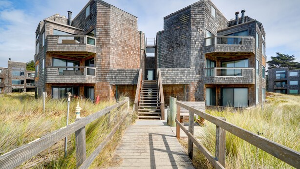 A modern building with a wooden deck leading to a staircase. - Oceanfront Watsonville Condo w/ Beach Access! (Watsonville)