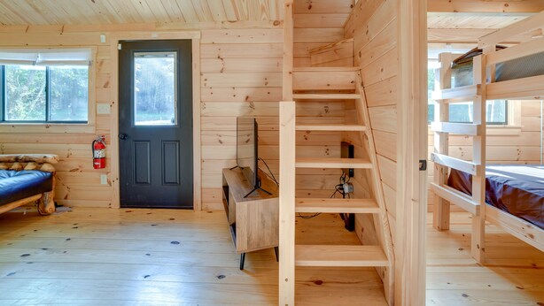 A wooden cabin interior with a bunk bed, a desk, and a staircase. - Catskills Tiny Home Cabin: Surrounded by Nature! (Franklin)