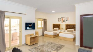 Een hotelkamer met twee bedden, een bureau, een televisie en een balkon.