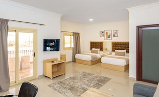 Habitación de hotel con dos camas, un escritorio, un televisor y un balcón.