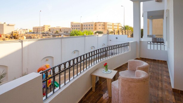 Een balkon met uitzicht op gebouwen, een tafel met een vaas en twee stoelen.