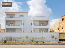 Un edificio residencial moderno de varios pisos con balcones y techo plano.