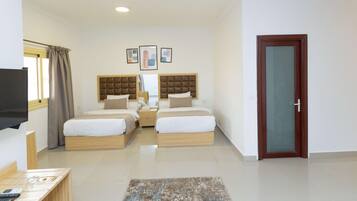 A hotel room with two beds, a TV, a desk, and a door.