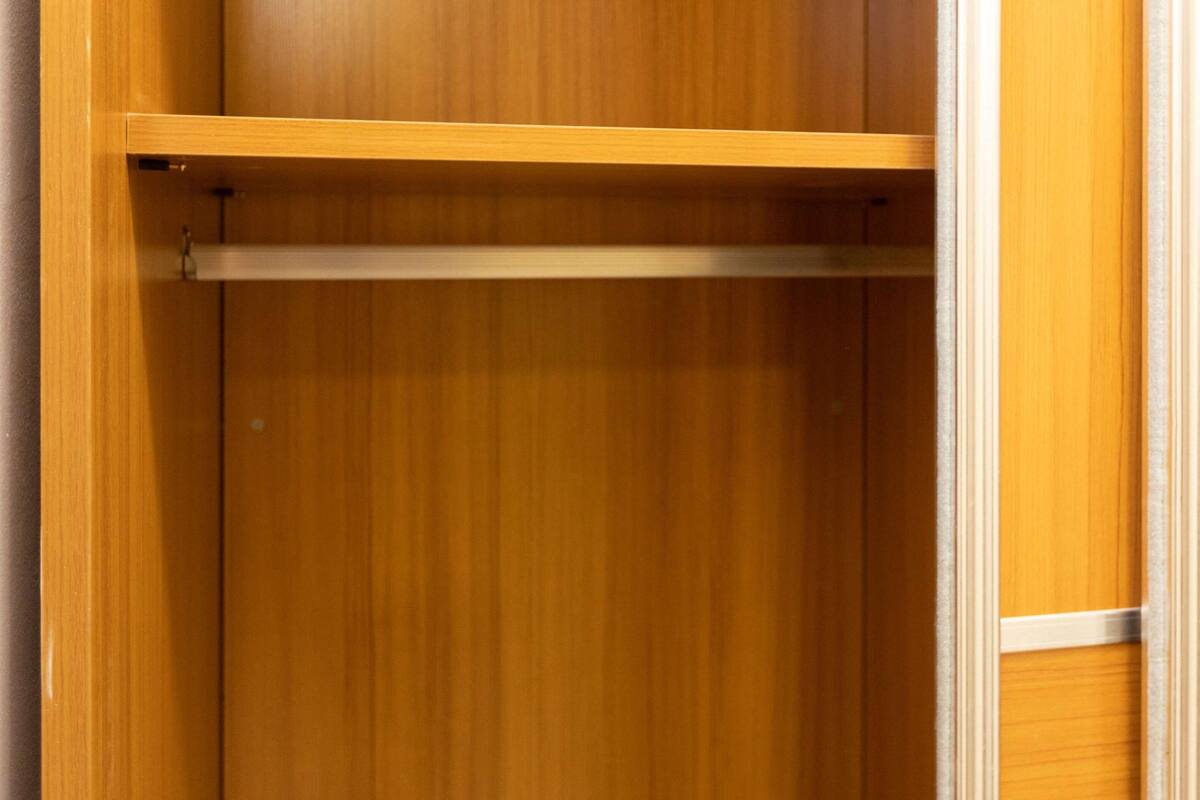 A wooden wardrobe with a single shelf.