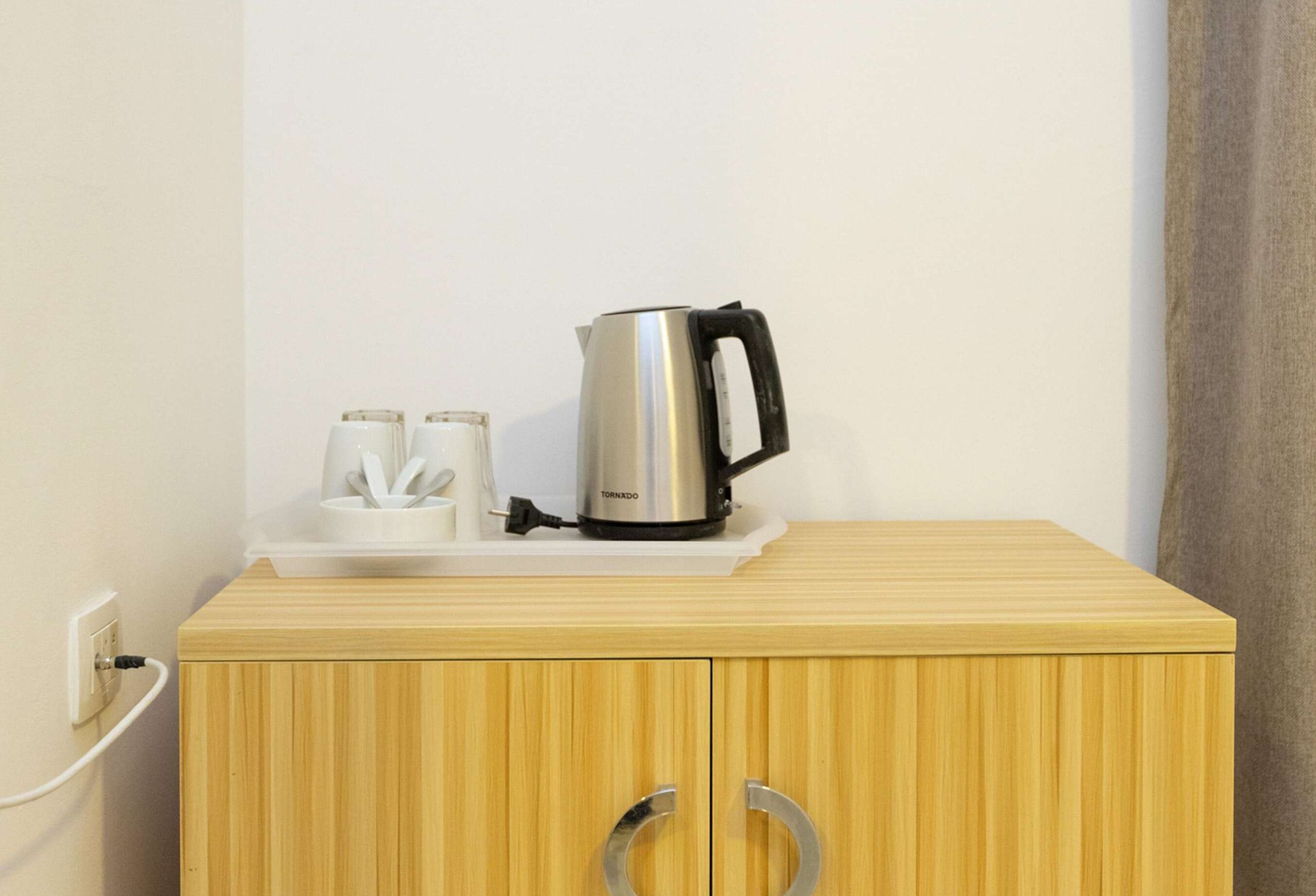 Un mueble de madera con una tetera y dos tazas encima.