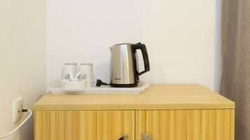 Un mueble de madera con una tetera y dos tazas encima.