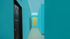 A hallway with teal walls and a tiled floor, leading to a door with a yellow curtain. - Hotel O Sidikalang Near KEJAKSAAN NEGERI DAIRI (Kota Sidikalang)