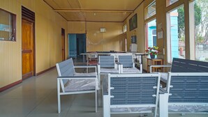 A hotel lobby with rows of white chairs, a reception desk, and large windows offering views of the outside. - Hotel O Sidikalang Near KEJAKSAAN NEGERI DAIRI (Kota Sidikalang)