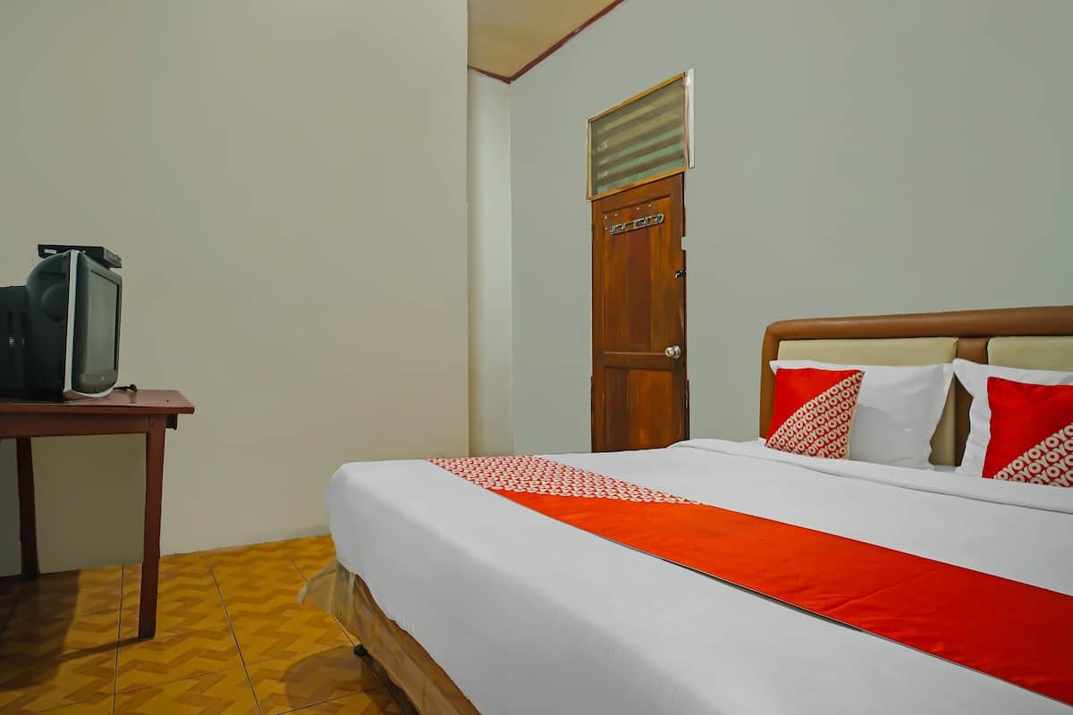 A hotel room with a bed, a wooden table, and a television.