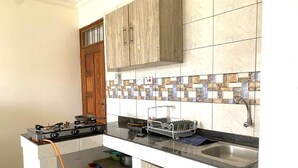 A compact kitchen with a gas stove, a sink, and wooden cabinets. - Aval Homes-Modern 1 bedroom apartment in Bamburi (Mombasa)